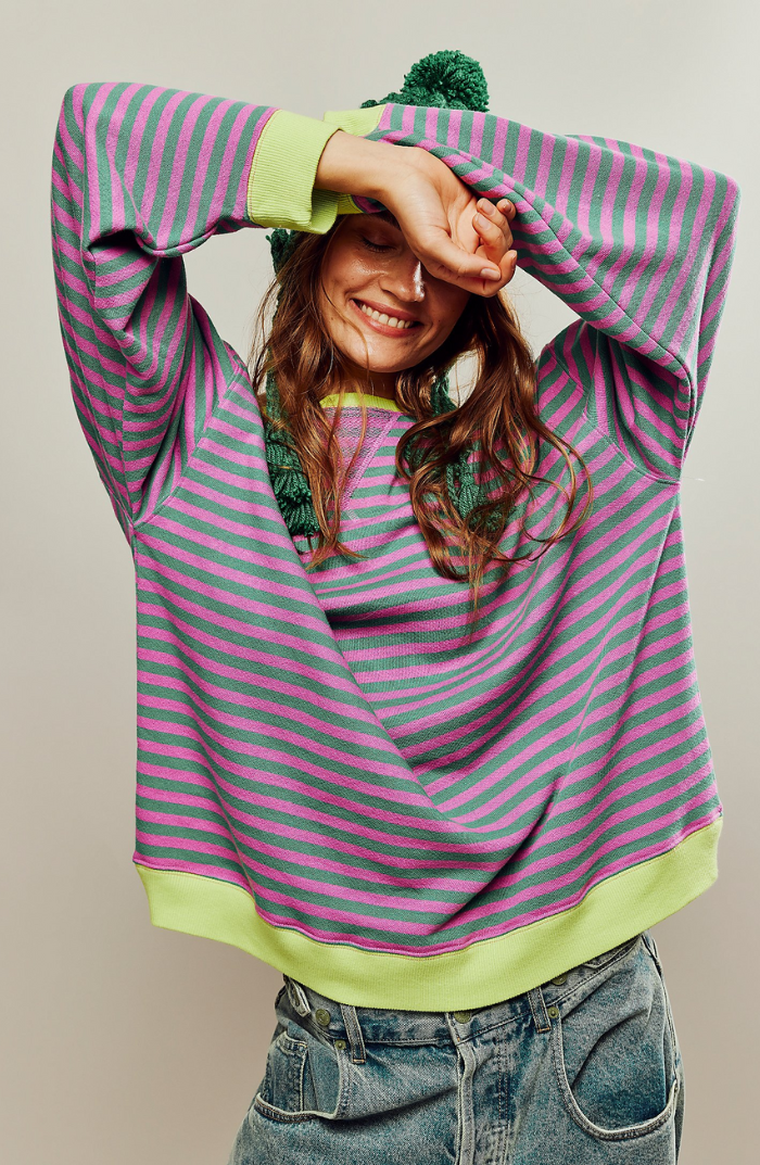 Fien gestreepte oversized sweater met groene en roze strepen, vooraanzicht met armen omhoog